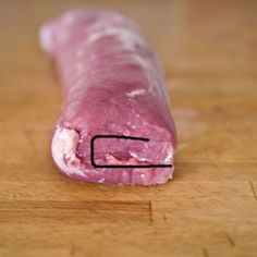 a piece of meat on a wooden surface with a line drawn across the end of it