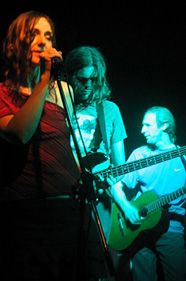 two people on stage singing and playing guitar