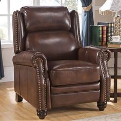 a brown leather recliner chair in front of a window