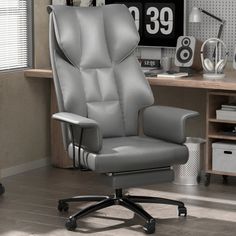 a gray office chair sitting in front of a desk with a clock on the wall