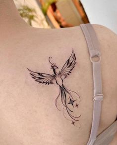 the back of a woman's shoulder with a bird tattoo on her left side