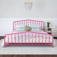 a pink metal bed frame in a white room with wallpaper and flowers on the walls