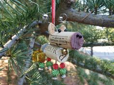 a wine cork ornament hanging from a pine tree with other ornaments on it