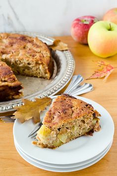 a piece of cake on a plate next to an apple pie and autumn leaves with apples in the background