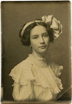 an old photo of a woman with a bow in her hair and wearing a white dress