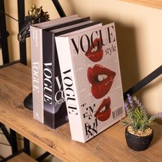 two books sitting on top of a wooden shelf next to a potted succulent