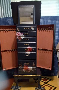 an antique jewelry cabinet with flowers painted on it