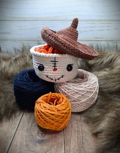 two balls of yarn and a crochet hat are on the floor next to each other