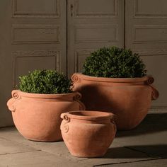 two large clay pots sitting next to each other on the ground in front of a door