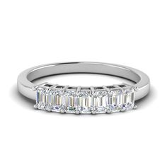 a white gold ring with three baguettes on the side and an emerald cut diamond in