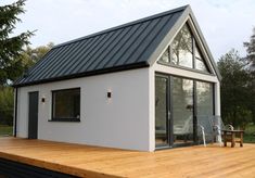 a small white house with a deck in the foreground