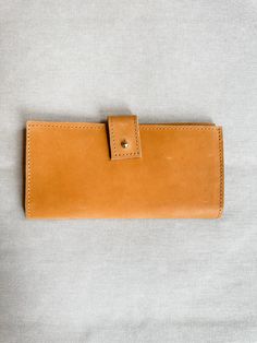 Introducing our custom line of leather handbags and accessories! Ethically made exclusively for Green Roost in Ethiopia and only available here! This is a limited edition collection, so snag yours before they're gone forever! This luxurious leather wallet will bring a timelessly classic look to your style. Crafted with quality Ethiopian leather & precision stitching, it strikes the perfect balance between elegance & durability. Its slim silhouette ensures convenience & its subtle embossed logo a Leather Travel Wallet In Cognac, Cognac Wallet With Leather Lining For Daily Use, Travel Wallet In Cognac With Leather Lining, Brown Leather Clutch For Daily Use, Brown Leather Clutch Wallet, Cognac Wallets With Interior Card Slots, Bifold Wallet In Vegetable Tanned Leather For Everyday Use, Vegetable Tanned Leather Bifold Wallet For Everyday Use, Cognac Leather Wallet For Daily Use