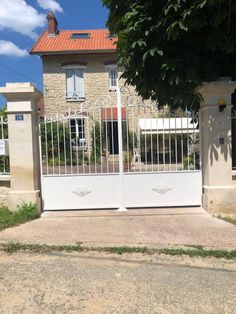 a white gate is in front of a house with an orange roof and brick walls