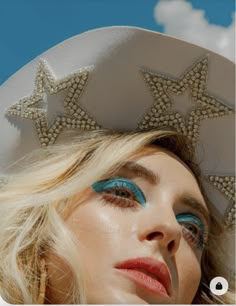 a woman with blue eye makeup and stars on her hat is posing for the camera