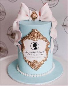 a blue cake with a pink bow on top and lady whitfield's logo