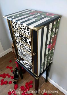 a black and white striped cabinet with red roses on the floor next to a pair of high heel shoes