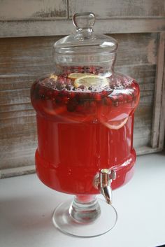 a red beverage dispenser with lemons and pomegranates