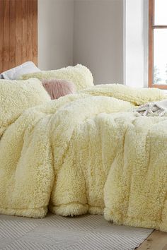 a bed covered in fluffy white blankets and pillows