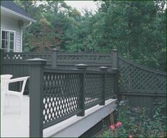 a white chair sitting on top of a wooden deck next to a lush green forest