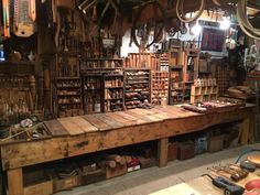 an old shop with lots of tools on the table and shelves full of wood planks