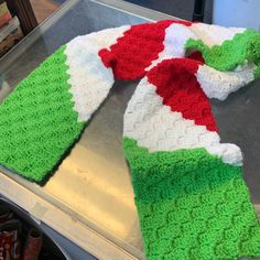 a green and white knitted scarf sitting on top of a metal counter next to soda cans