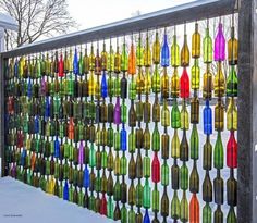 a fence made out of wine bottles is shown in front of the snow covered ground