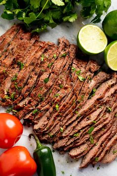 sliced flank steak with limes, tomatoes and jalapenos on the side