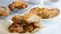 some fried food sitting on top of a white plate next to a cooling rack filled with sauce