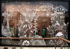 the window is decorated with white flowers and plants on it's glass display case