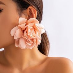 a close up of a woman wearing large flower earrings