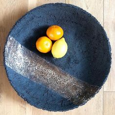 three oranges and one lemon in a blue bowl