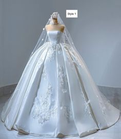 a white wedding dress with flowers on the skirt is displayed in front of a mannequin