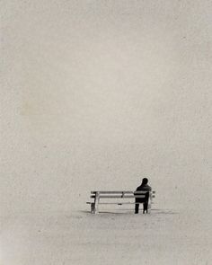 a person sitting on a bench in the snow