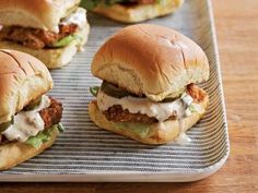 three sandwiches with meat, cheese and lettuce are on a tray ready to be eaten