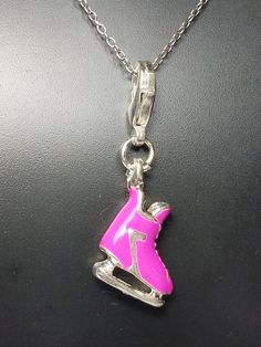 a necklace with a pink skateboard pendant on it's link chain that is attached to a black surface