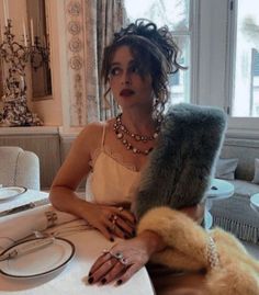 a woman sitting at a table with jewelry on it