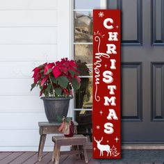 a red christmas sign sitting next to a potted plant in front of a door