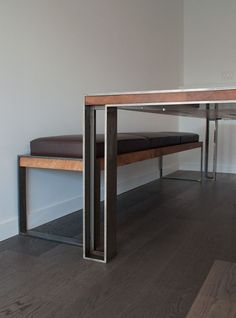 a wooden bench sitting on top of a hard wood floor next to a white wall