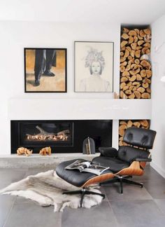 a living room with fireplace, chair and pictures on the wall in front of it