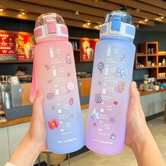 two people holding up water bottles with stickers on them