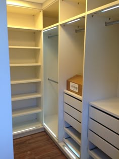 an empty walk in closet with white shelves and drawers