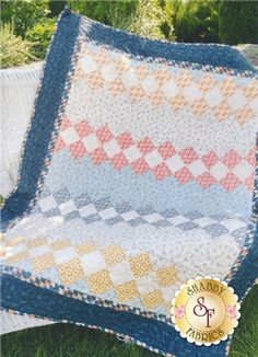 a blue and white quilt sitting on top of grass