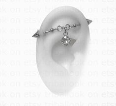 an ear with two piercings attached to it's sides, and a single crystal stone in the middle