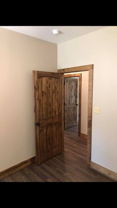 an empty room with wooden doors and hard wood flooring