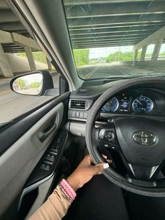 a woman driving a car with her hand on the steering wheel