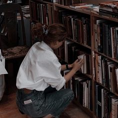 a woman kneeling down in front of a bookshelf