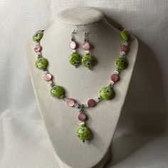 This Handmade Set Includes The Necklace And Earrings. The Necklace Features Lamp Work Glass Green W/Flowers Beads, Round Flat Pink Mother Of Pearl Shell, Small White Cats Eye, And Crystals. It’s Finished With A Pewter Toggle Clasp And Measures 22” Long. The Earrings Match The Necklace And Are Finished In Sterling Silver Hook Backs. Handmade Pink Czech Glass Jewelry, Pink Beaded Czech Glass Jewelry, Pink Flower Jewelry With Dangling Beads, Pink Flower-shaped Jewelry With Dangling Beads, Handmade Pink Czech Glass Necklaces, Handmade Pink Czech Glass Necklace, Green Flower-shaped Jewelry With Dangling Beads, Flowers Beads, Cats Eye