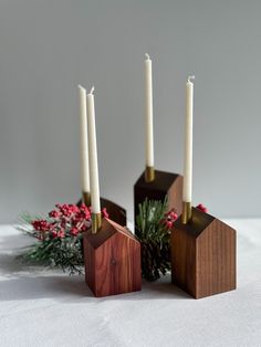 three candles are placed in wooden holders with pine cones and greenery on the table