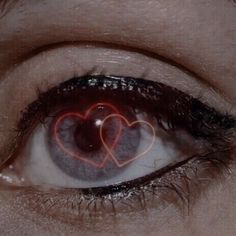 a person's eye with two hearts drawn on the side of their iris lens