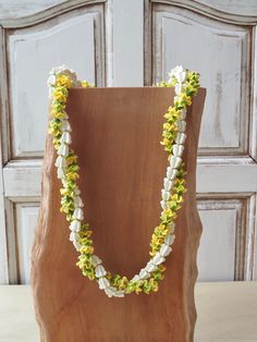 a wooden vase with flowers in it sitting on a table next to a wall and door